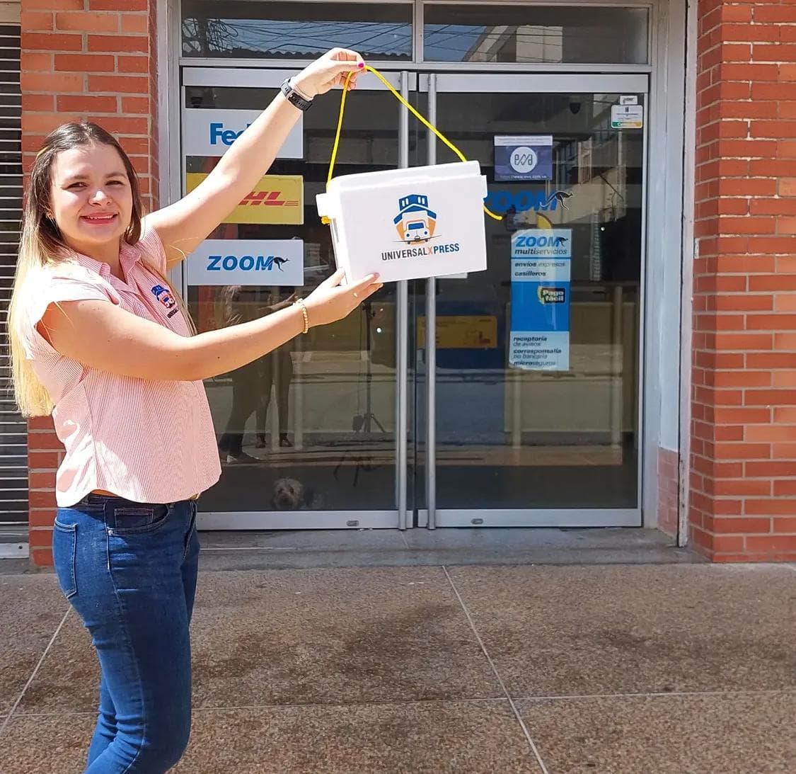 Miembro del equipo de Universal Xpress con un casillero de la marca en la entrada de la agencia
